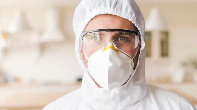 Technician in a mask and protective suit